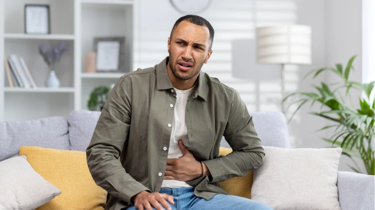 Homem sentado com a mão na barriga
