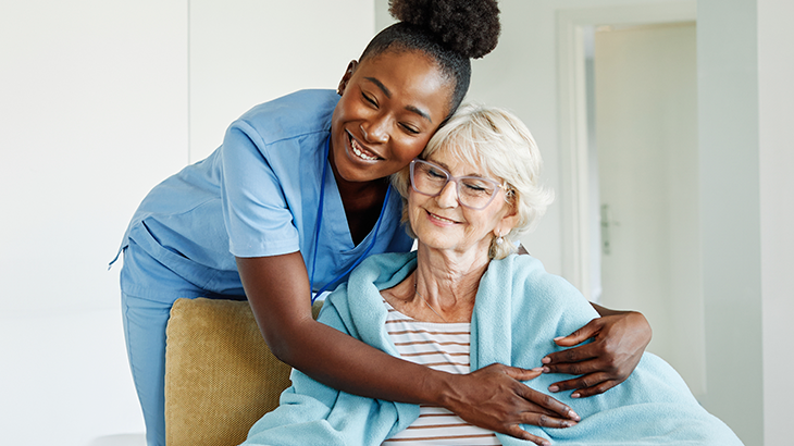Enfermeira abraçando a idosa que está sentada