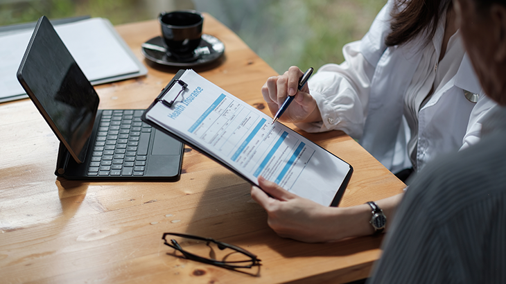 Médica sentada segurando um papel e mostrando para a paciente sentada